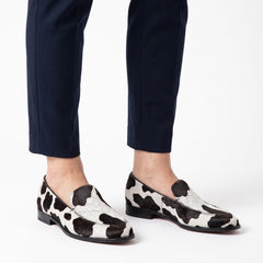 Delia cow-print pointed loafers worn on feet, hero product image