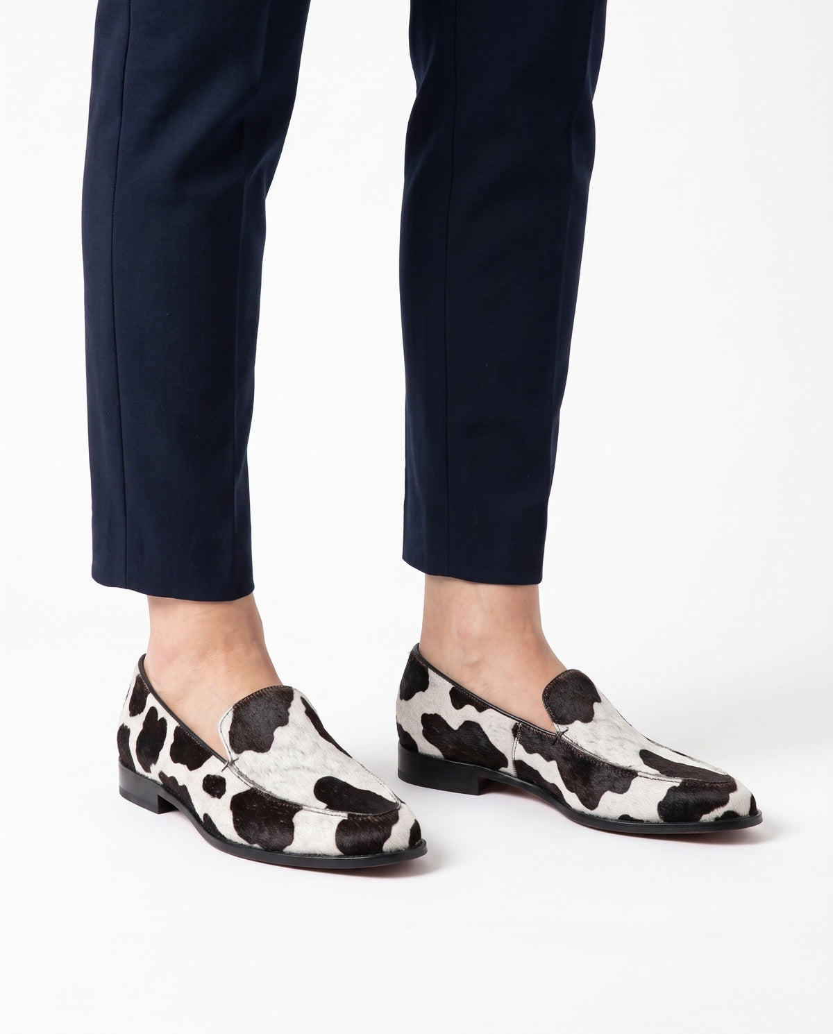Delia cow-print pointed loafers worn on feet, hero product image